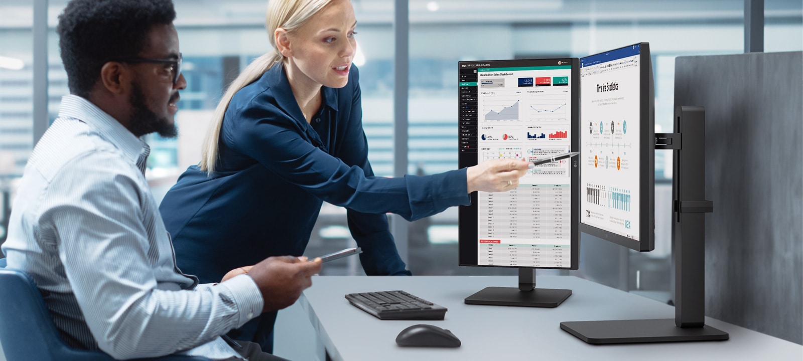 Dvoje zaposlenih razgovara dok gleda u monitor u kancelariji.