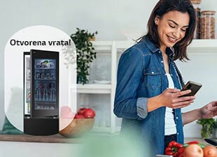 Slika žene koja prima obaveštenje na svoj pametni telefon iz aplikacije LG ThinQ o tome da su vrata frižidera ostavljena otvorena dok ona kuva.
