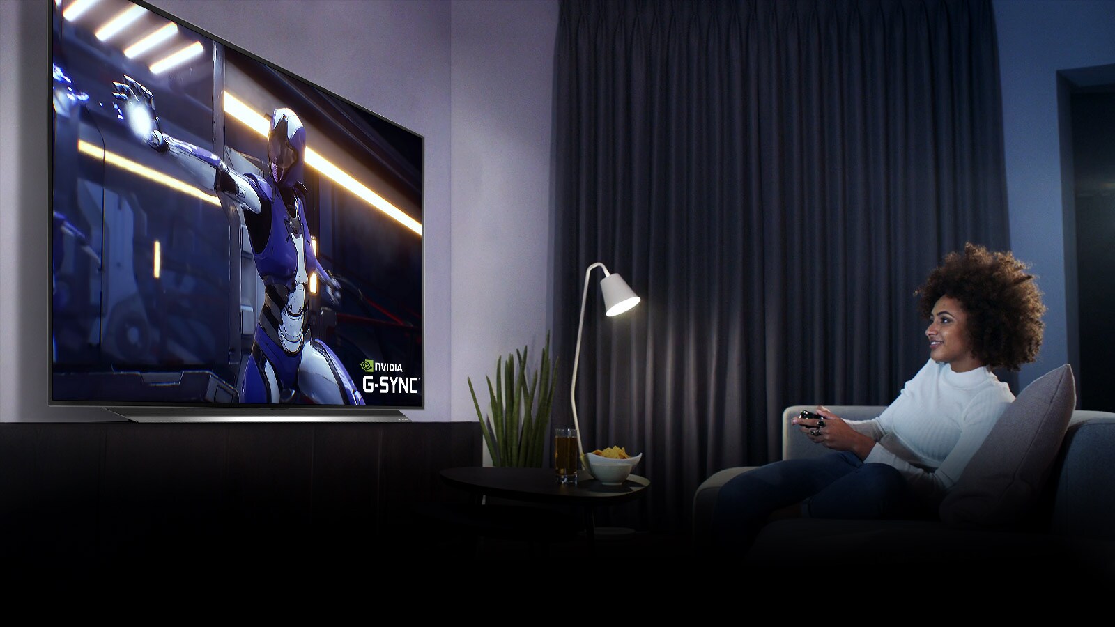 Žena sjedi na sofi, drži džojstik dok igra igru na TV ekranu