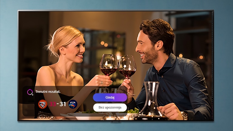 Muškarac i žena se kuckaju čašama na TV ekranu dok se prikazuje trenutni rezultat izabranog sportskog događaja