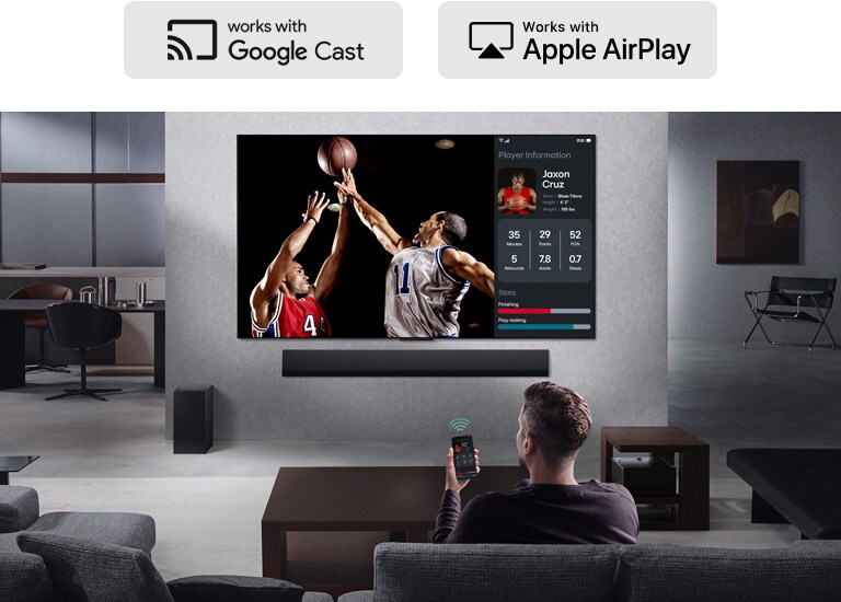 Osoba u dnevnoj sobi drži telefon. Na telefonu je ikona prebacivanja sadržaja koja prikazuje da se ekran telefona preslikava na TV. Na TV-u je košarkaška utakmica, sa strane je preslikani ekran, sa statistikom igrača. 