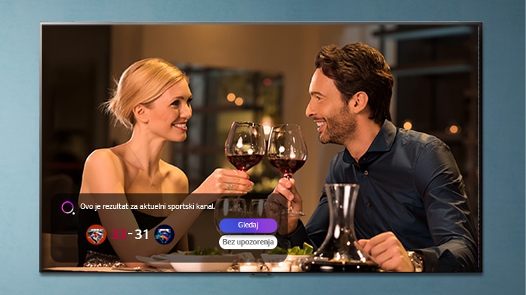 Muškarac i žena kuckaju čašama na TV ekranu dok se prikazuju upozorenja u vezi sa sportskim događajem