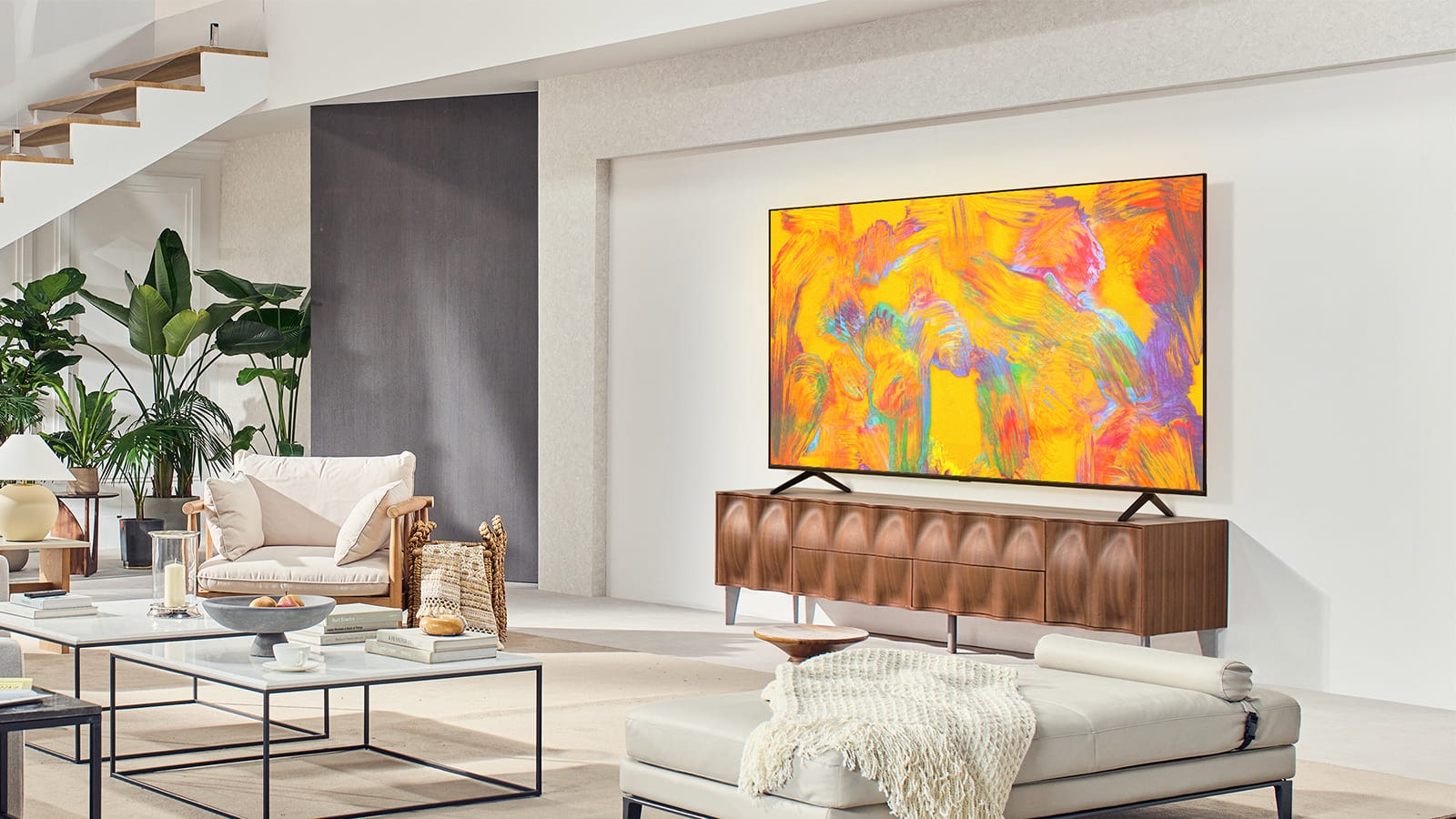 LG QNED TV stoji iznad fioke police za televizor u udobnom životnom prostoru. LG QNED TV prikazuje apstraktnu pozadinu u narandžastoj, žutoj, ljubičastoj i roze boji.