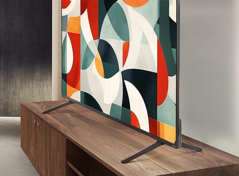 LG QNED TV stoji iznad fioke police za televizor u savremenom životnom prostoru. LG QNED TV prikazuje apstraktnu pozadinu u zelenoj, crvenoj i narandžastoj boji.