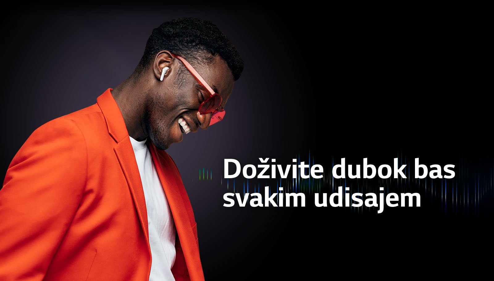 Muškarac u narandžastom odelu sluša muziku preko TONE Free bubica.