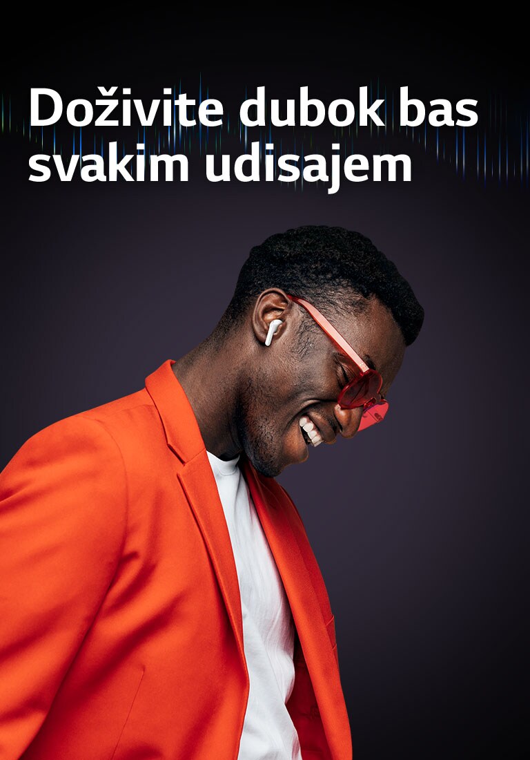 Muškarac u narandžastom odelu sluša muziku preko TONE Free bubica.