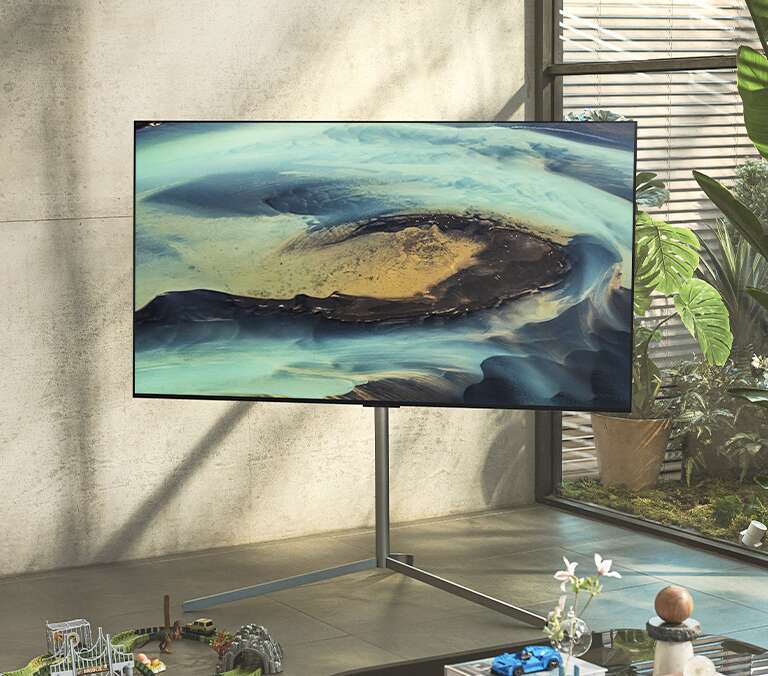 Gallery postolje postavljeno u uglu osvetljene i osunčane sobe sa montiranim LG televizorom, prostoru daje elegantan izgled.