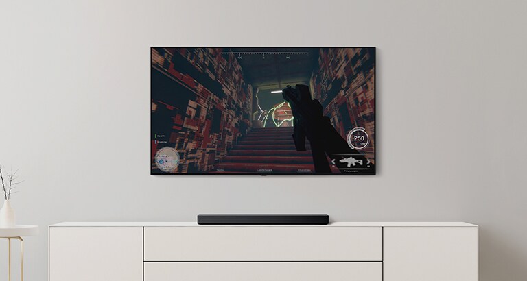 U dnevnoj prostoriji nalaze se televizor i Soundbar zvučnik. FPS igra prikazuje se na TV ekranu i bira se kanal sa fudbalskom utakmicom. (reprodukcija video-zapisa)