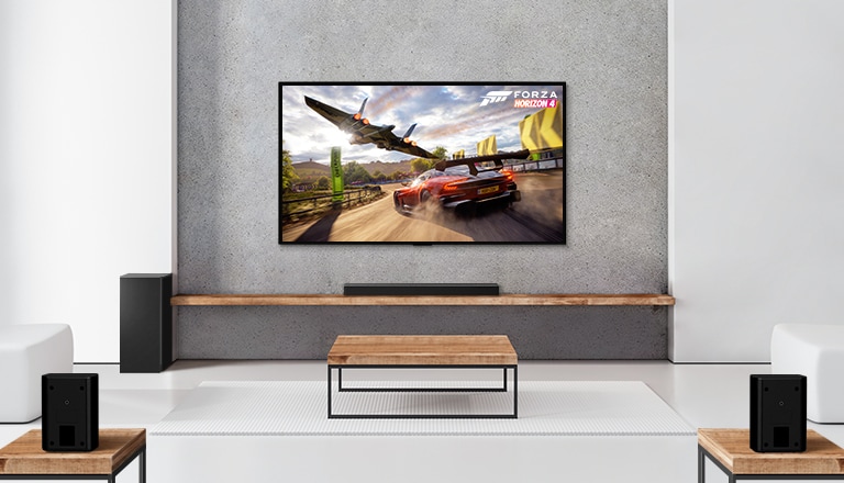 Komplet 2 zadnja zvučnika, niskotonac i Soundbar zvučnik i televizor nalaze se u beloj dnevnoj sobi. Na TV ekranu prikazuju se automobil u pokretu i svemirski brod.