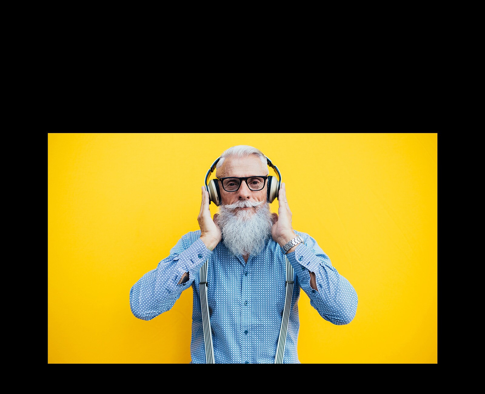 Deka sedi ispred žutog zida – sa slušalicama.