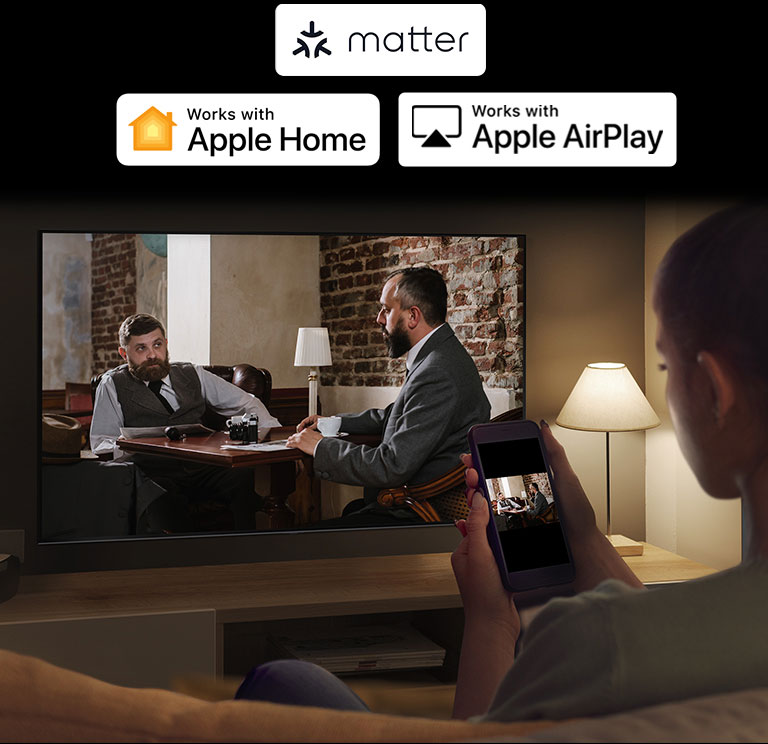 Prikazana je žena u mračnoj prostoriji koja gleda video-sadržaj sa telefona na televizoru pomoću preslikavanja.