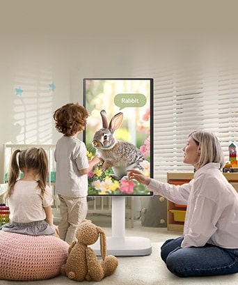 Тази снимка показва жена и три деца, играещи с LG Smart Monitor Swing.