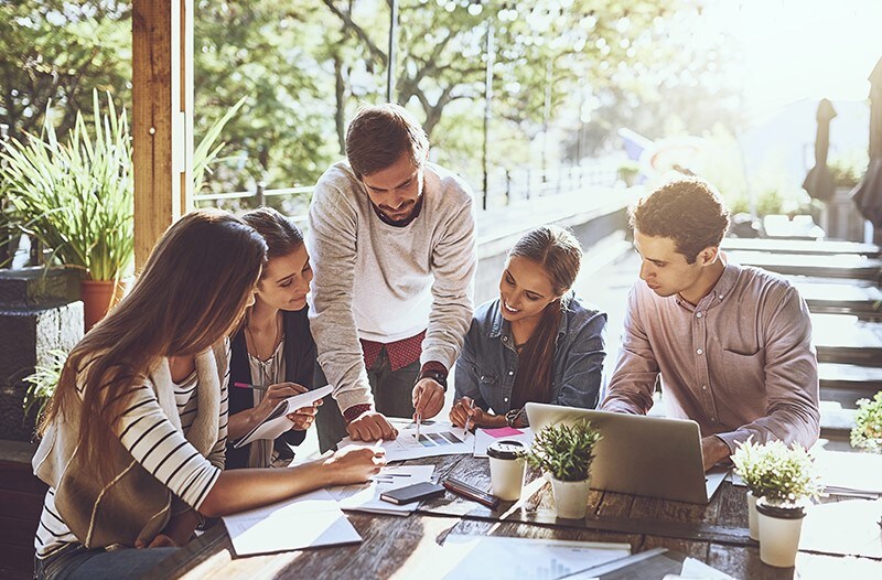 A group of colleagues look over some documents together, surrounded be greenery and clean air. That's our hope for the future as we work towards a more sustainable world