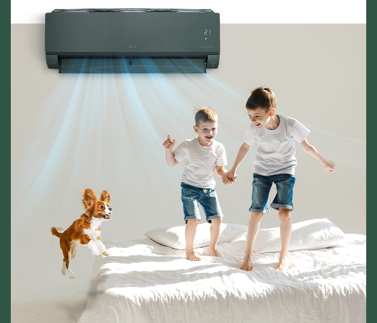 Дети и собака прыгают на кровати. Из кондиционера ARTCOOL выходит поток прохладного воздуха.