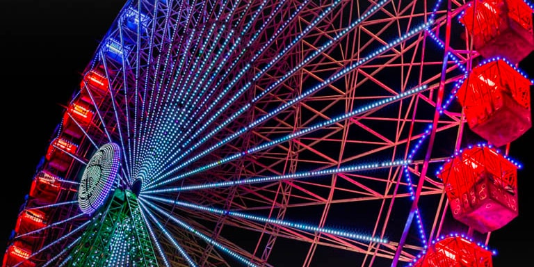 Слегка потускневшее колесо обозрения подсвечивается в ночное время, а разноцветные искры появляются в левой части экрана и перемещаются по нему. По мере прохождения разноцветных искр экран превращается из тусклого в яркий, насыщенный цветами.