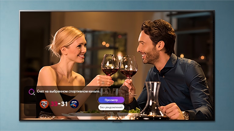 Мужчина и женщина чокаются бокалами на экране телевизора, на котором отображается уведомление о спортивном соревновании
