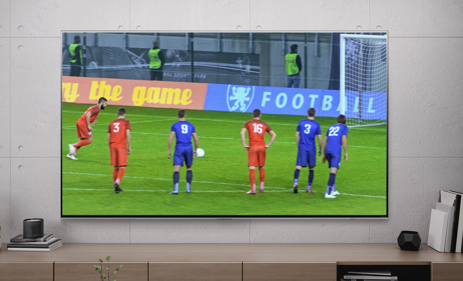 Экран телевизора, демонстрирующий игрока, забившего гол в пенальти (просмотр видео).