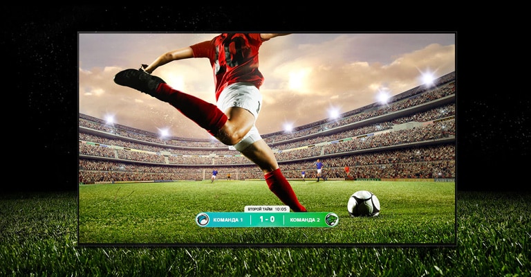 Изображение телевизора с игрой в футбол и игроком на красной полосе, который собирается пнуть мяч через стадион. В нижней части экрана виден счет игры. Зеленая трава выходит за пределы экрана и отображается на черном фоне.