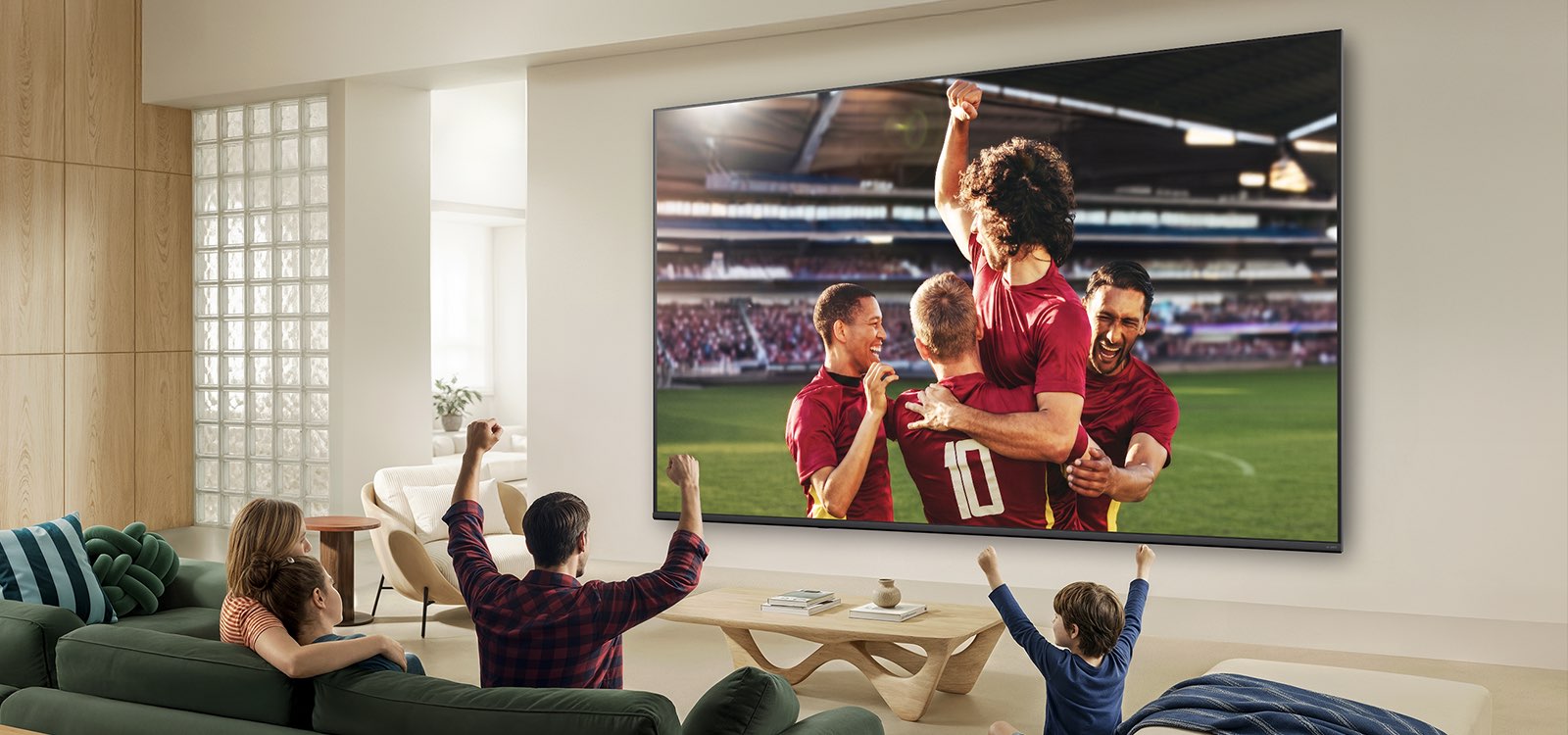 Ультрабольшой телевизор LG QNED evo AI Mini LED QNED8M показывает захватывающую крупномасштабную футбольную игру с улучшенным качеством изображения и яркими цветами, а семья вместе радуется на диване в гостиной.