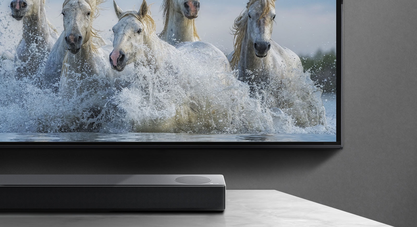 Нижняя половина экрана и нижняя половина саундбара На экране телевизора показаны белые кони, скачущие над водой. 