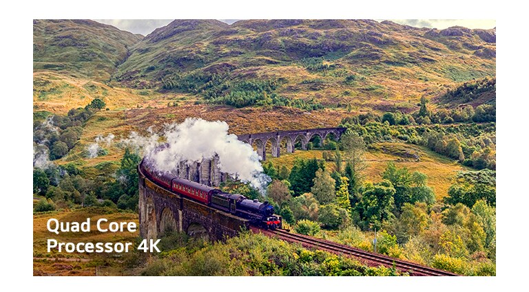 Поезд, испускающий пар на рельсах, находится в середине горы с надписью Quard Core Processor 4K в левом нижнем углу.