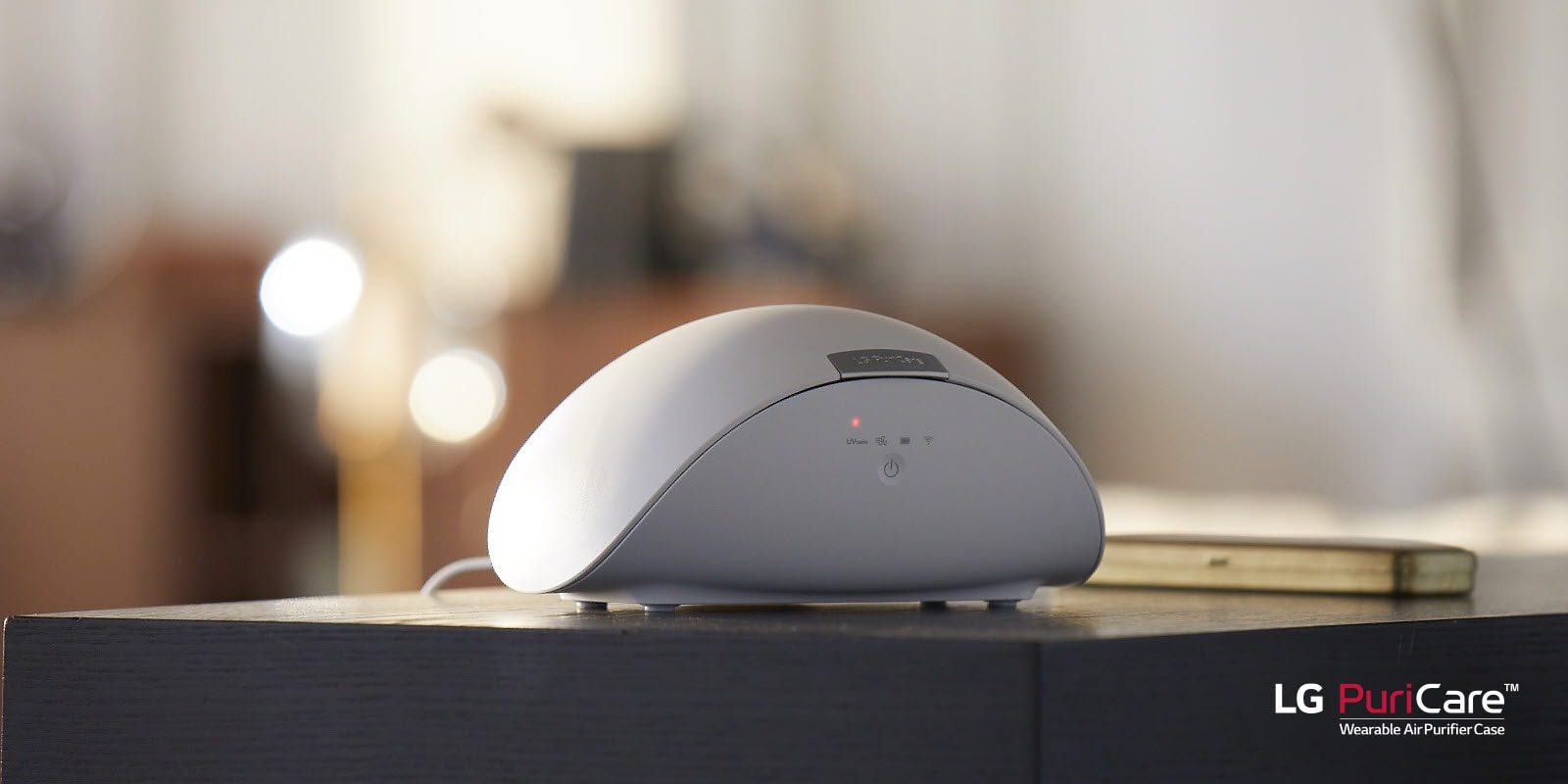 Футляр для носимого очистителя воздуха LG PuriCare стоит на столе. На дисплее горит красный свет.