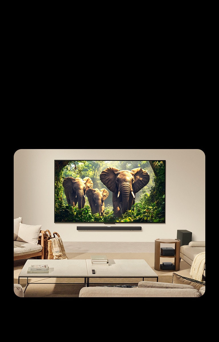 Телевизор LG QNED9M с настенным креплением в гостиной. Блок Zero Connect аккуратно размещён под приставным столиком вместе с другими периферийными устройствами.
