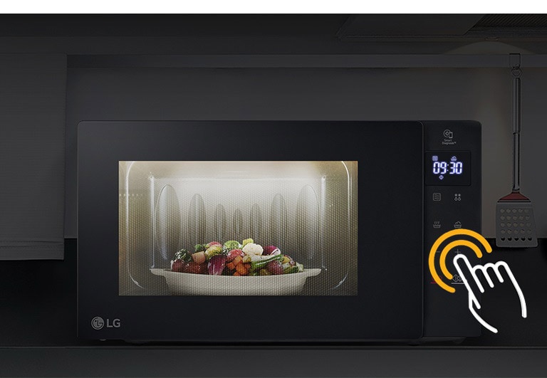 Процесс приготовления еды в камере микроволновой печи с LED подсветкой на кухне, где выключен свет.