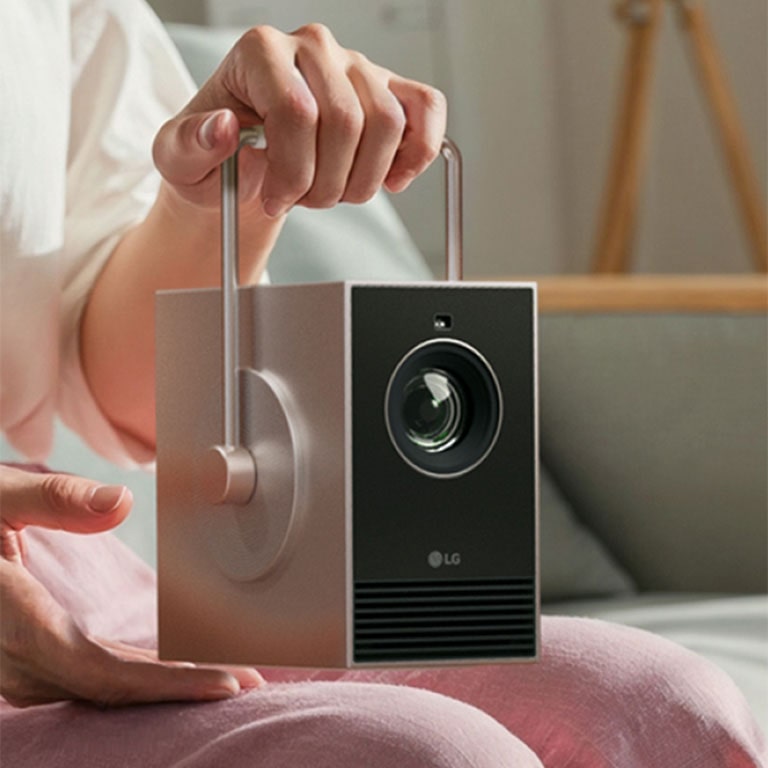 Изображение человека, который держит LG CineBeam Q за ручку, поворачивающуюся на 360°.