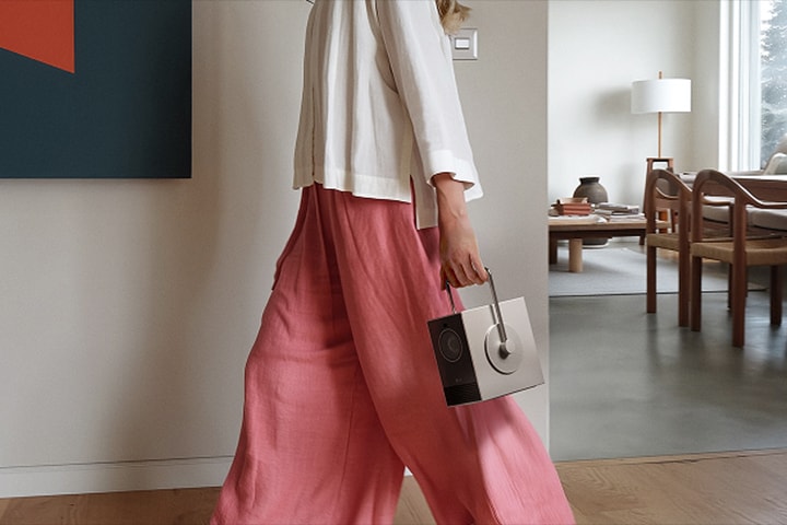 Изображение человека, несущего LG CineBeam Q за ручку.