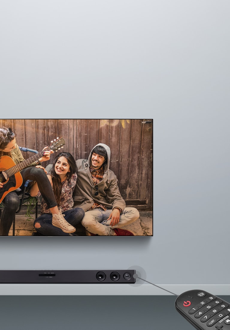 Закрепленный на серой стене телевизор LG, на экране которого демонстрируется фильм. Под ним находится саундбар LG. В правой части изображения показан пульт ДУ. Показана линия, соединяющая пульт с саундбаром, демонстрирующая, что пользователи могут управлять саундбаром с пульта ДУ.