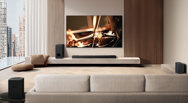 Телевизор LG TV, звуковая панель LG Soundbar, сабвуфер и задние колонки находятся в современной городской квартире. Фон затемняется, и поверх изображения с телевизора LG TV появляется наложение в виде сетки, как при сканировании пространства. Пунктирная линия идет от одного из задних динамиков, чтобы показать, что два задних динамика расположены линейно. Белые звуковые шарики собираются вместе и образуют волны, наполняя комнату звуком.
