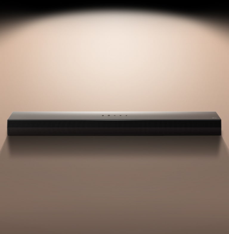 Изображение звуковой панели LG Soundbar на черном фоне, освещенном прожектором. 