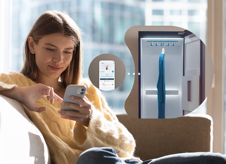 Женщина сидит на диване и контролирует работу LG Styler со смартфона