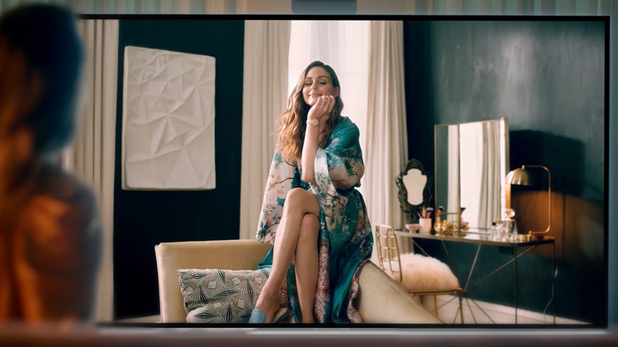 Оливия Палермо смотрит на свое изображение на экране телевизора LG SIGNATURE OLED 8K, зачарованная глубоким черным, яркими цветами и реалистичностью картинки.