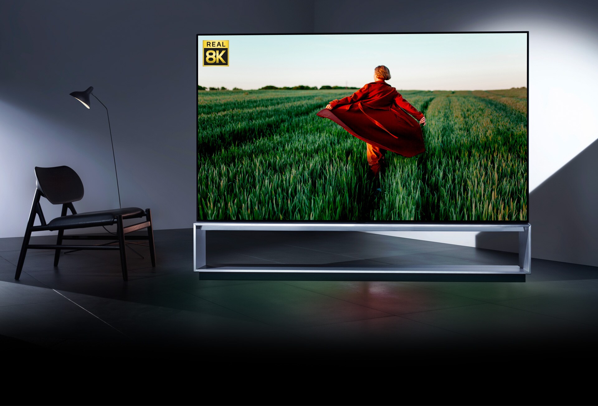 An LG OLED 8K TV, showing 8K realism via an image of a woman in a red trench coat running in a green rice field
