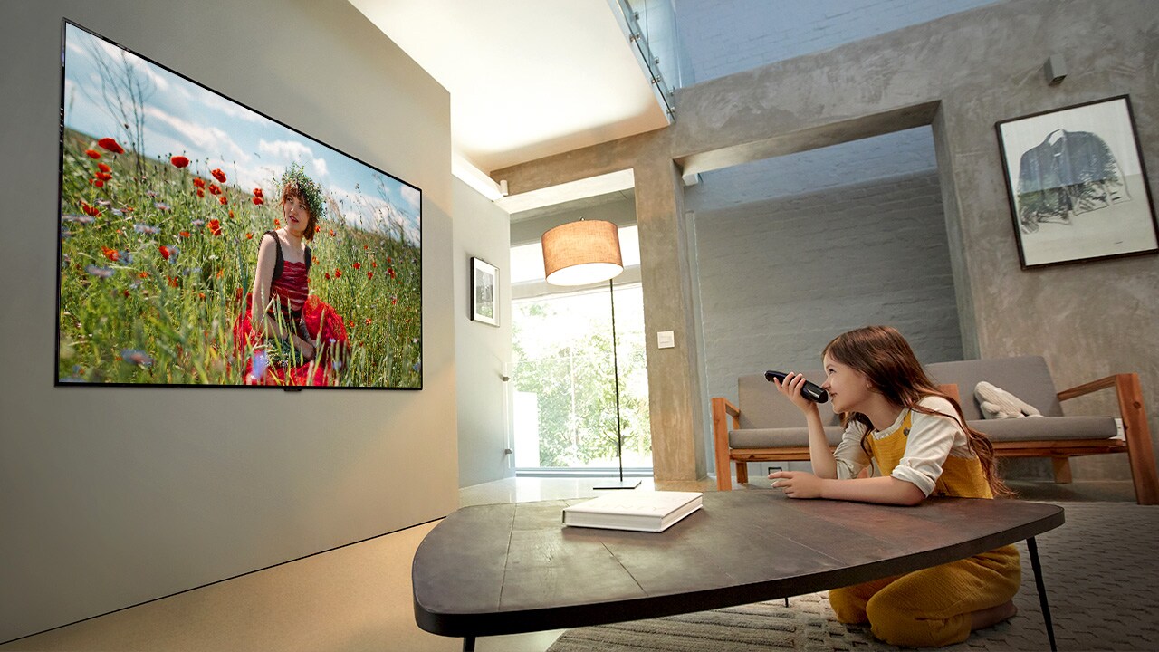 Girl is watching Disney animation at its best quality on TV with her arm leaning on the living room table (move the slide)