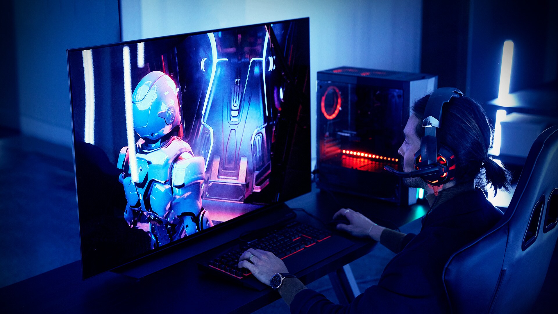 A man playing at gaming station set up with a 48-inch LG OLED TV CX, desk, and chair