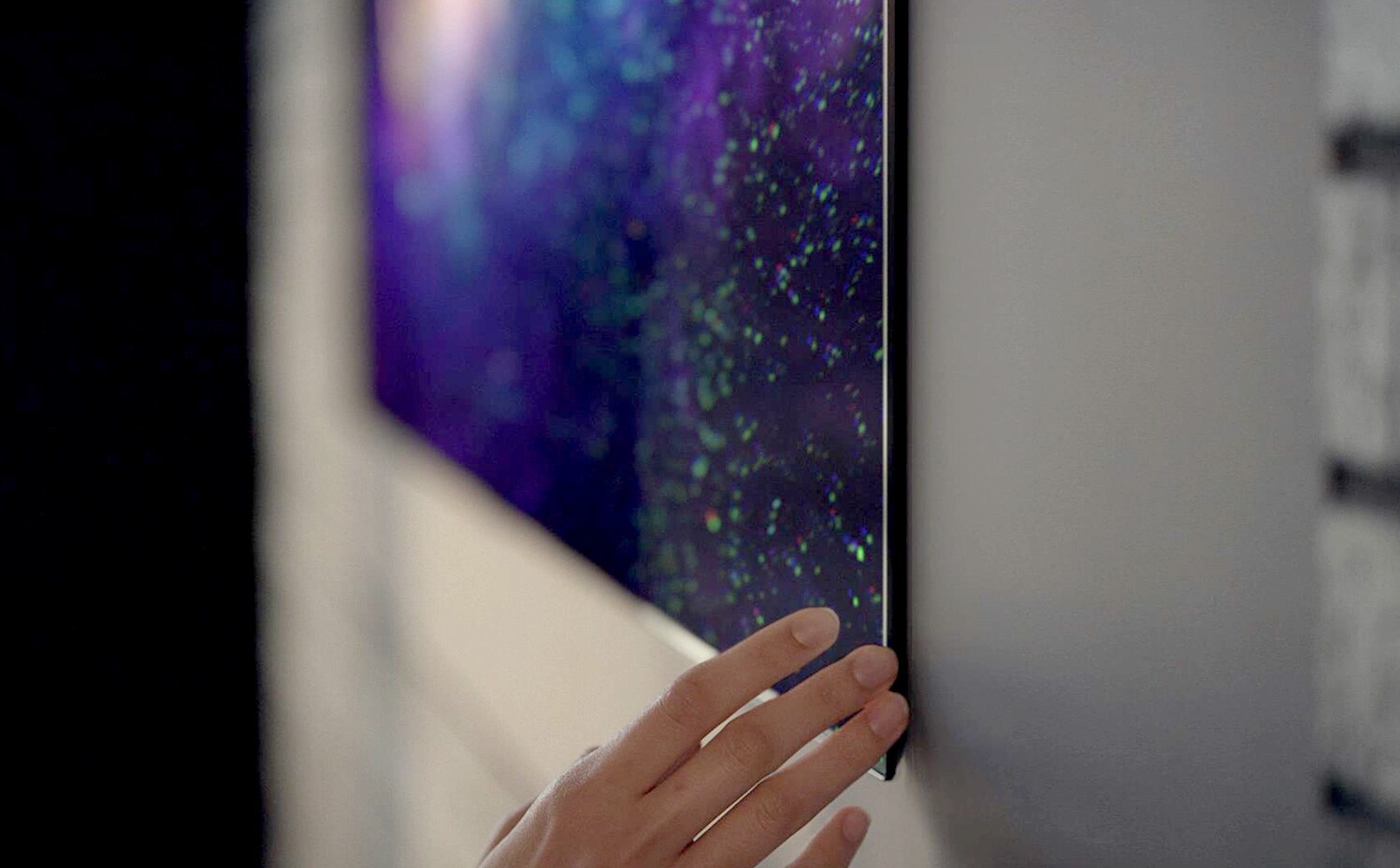 Крупный план руки у кромки телевизора Gallery Design. Ясно видно его точное прилегание к стене.