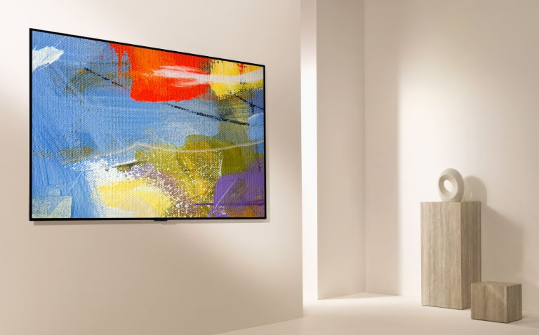 Сделанное под углом широкоугольное фото телевизора Gallery Design на стене с картиной на экране