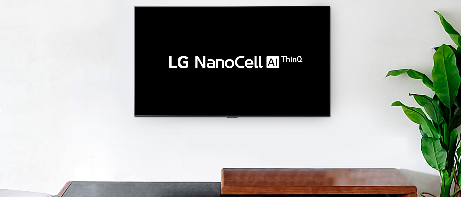 Väggmonterad TV som visar LG OLED AI ThinQ:s logotyp mot svart bakgrund
