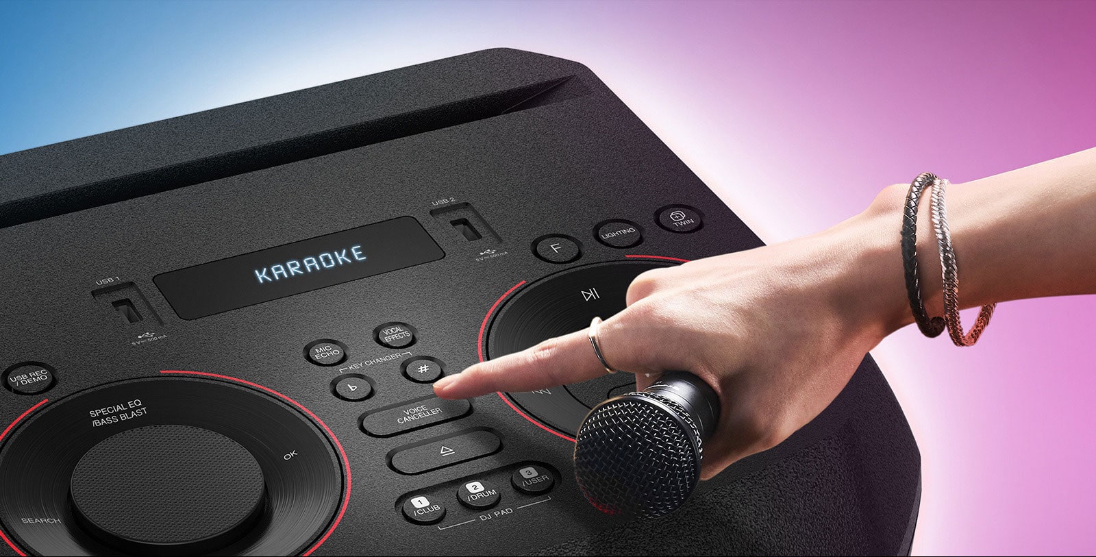 Ruka držiaca mikrofón stláča tlačidlo funkcie na odstránenie hlasu zo skladby v hornej časti reproduktora LG XBOOM.