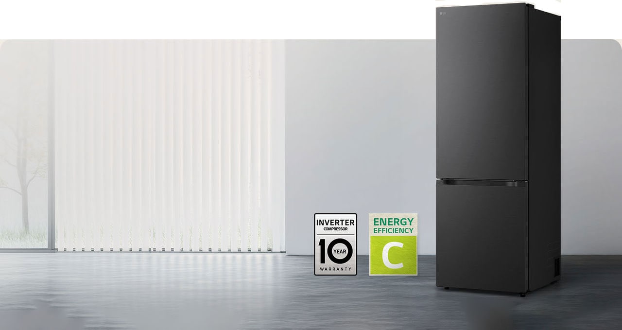 Matná čierna chladnička so spodnou mrazničkou LG (GBBW726AEV), pohľad spredu v svetlej miestnosti s vertikálnymi žalúziami s ikonami 10-ročnej záruky na kompresor a energetickej účinnosti A dole