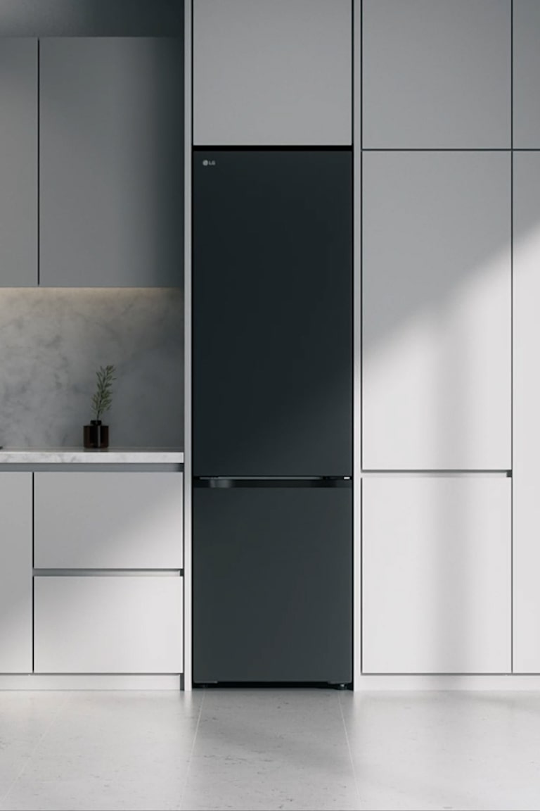 Matná čierna chladnička so spodnou mrazničkou LG  vstavaná v sivých skrinkách vedľa mramorovej pracovnej dosky s indukčnou varnou doskou a veľkým oknom vpravo