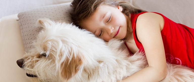 Dievča kľudne spí a objíma svojho psa. 