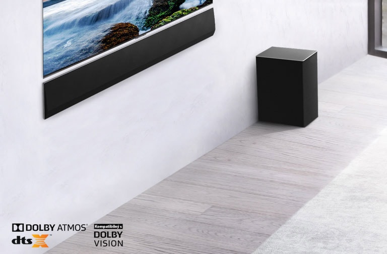 Televízor a LG Sound Bar sú osadené na stene so subwooferom umiestneným vpravo pod nimi. Na obrazovke televízora je západ slnka na mori.