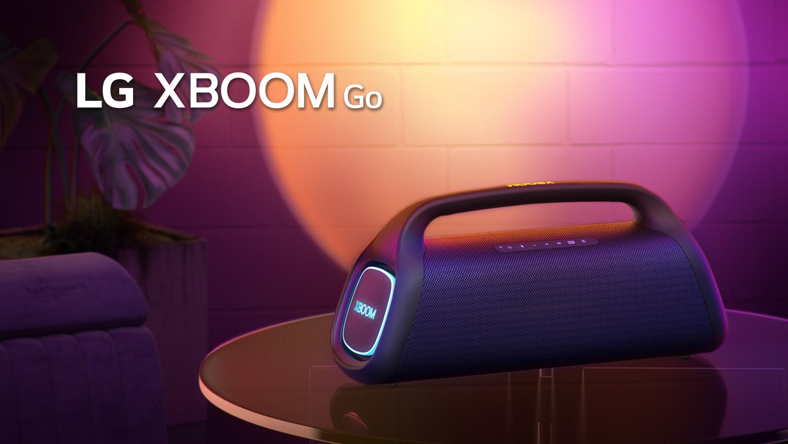 LG XBOOM Go XG9 je položený na kovovom stole so zapnutým oranžovým svetlom. Za stolom je stena osvetlená scénickým svetlom.