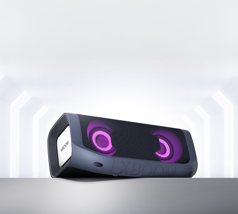 Pohľad z uhla na reproduktor LG XBOOM Go s purpurovým osvetlením položený na sivej polici.