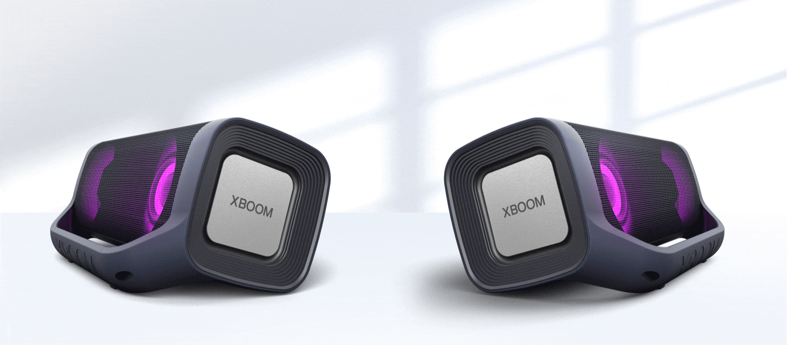 Na bielom pozadí sú zobrazené dva reproduktory LG XBOOM Go smerujúce od seba. Oba majú purpurové osvetlenie.