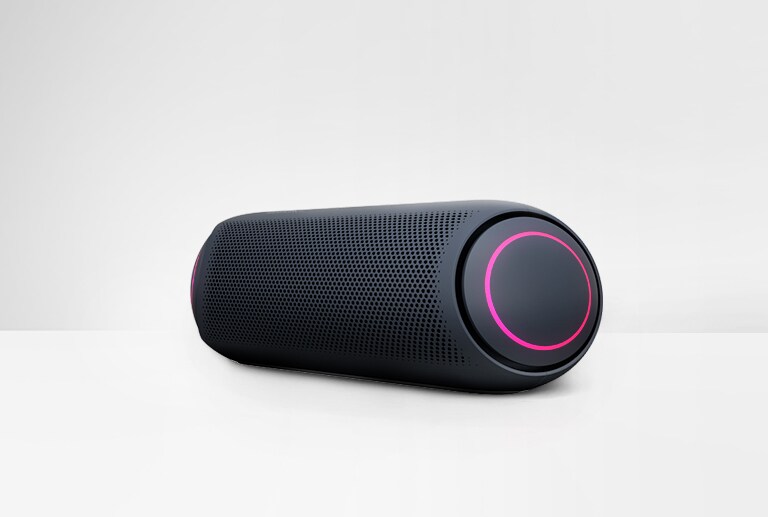 Pohľad z uhla na reproduktor LG XBOOM Go PL5 na bielom pozadí s purpurovým osvetlením.